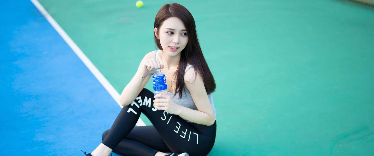 坐在网球场上的可爱长发美女带鱼屏高清壁纸